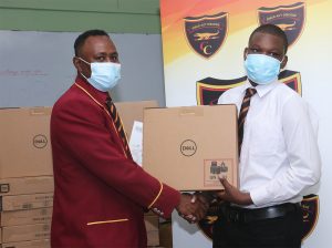 Dr. Richard Meghoo, President of the Montego Bay Chapter of the Old Boys Association presenting one of the machines to a student of Cornwall College